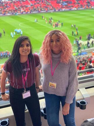 Nutmegs co-founders Ammarah and Hayley standing together overlooking the pitch at Wembley Stadium.